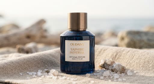 Oudany Saphire Imperial deep blue perfume bottle on natural linen beside sea salt crystals